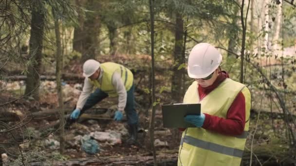 Écologiste homme en vêtements de travail et casque mesure le diamètre de la décharge de plastique — Video