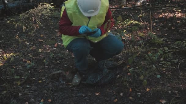 Γυναίκα περιβαλλοντολόγος στα ενδύματα εργασίας και κράνος ρεκόρ αδίκημα - ρύπανση των δασών — Αρχείο Βίντεο