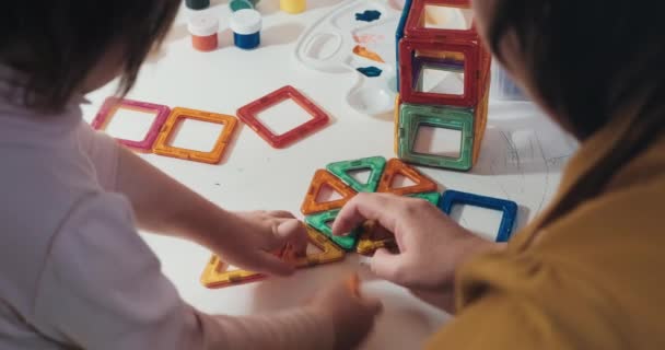 Barn med sin mamma samlar en magnetisk konstruktör, närbild, bakre vy — Stockvideo