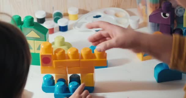 Pedagógus a gyermekek fejlődő kör összegyűjti a műanyag konstruktor a gyermek — Stock videók