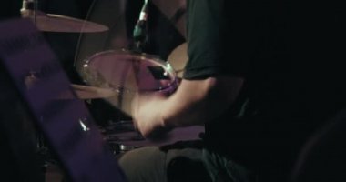 Konser, davul çalan bir adam, çok renkli bir ışık yanıp sönüyor.