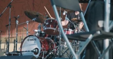Konser, davul çalan bir adam, çok renkli bir ışık yanıp sönüyor.