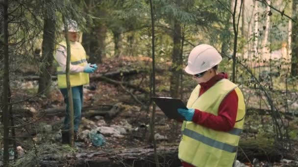 Mężczyzna, kobieta ekolodzy dokumentują obrazę - zanieczyszczenie lasów i wydają grzywnę — Wideo stockowe