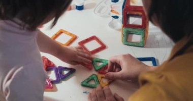 Çocuk annesiyle birlikte manyetik bir yapıcı topluyor, yakın çekim, dikiz görüntüsü.