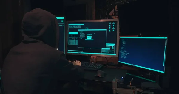 Kaputtaki bir bilgisayar korsanı bilgisayar ekranlarının önünde oturur ve veritabanlarını hackler