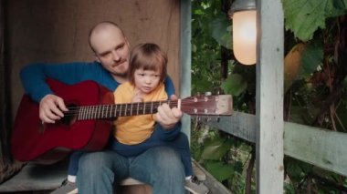 Babam küçük çocuğu için akustik gitar çalar. Eski, eski bir dekor
