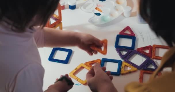 Child with his mother collects a magnetic constructor, close up shot, rear view — Stock Video
