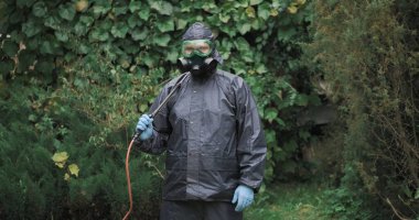 Kimyasal koruma giysisi, solunum cihazı ve gözlüklü bir adam.