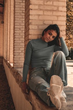 Parkta yürüyen ve kameraya bakan bir kız oturuyor ve arka planda doğa ile duruyor..