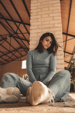 Parkta yürüyen ve kameraya bakan bir kız oturuyor ve arka planda doğa ile duruyor..