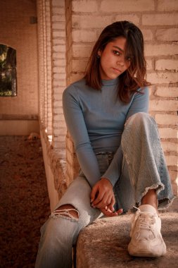 Parkta yürüyen ve kameraya bakan bir kız oturuyor ve arka planda doğa ile duruyor..