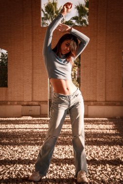 Parkta yürüyen ve kameraya bakan bir kız oturuyor ve arka planda doğa ile duruyor..