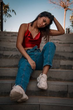 Parkta yürüyen ve kameraya bakan bir kız oturuyor ve arka planda doğa ile duruyor..