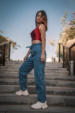 Parkta yürüyen ve kameraya bakan bir kız oturuyor ve arka planda doğa ile duruyor..