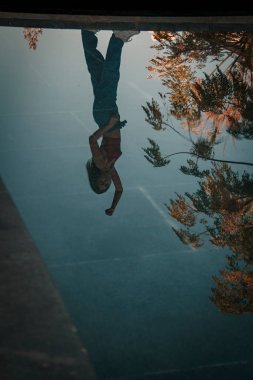 Parkta yürüyen ve kameraya bakan bir kız oturuyor ve arka planda doğa ile duruyor..