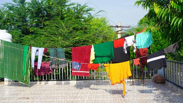 Laundry drying on the balcony of a building. Laundry line with clothes on green tree background