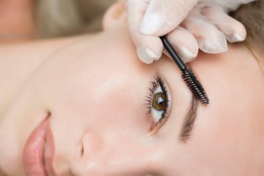 Genç bir kadın kaş düzeltme, kınayı boyama ve kaplama işleminden geçiyor. Yakın plan.