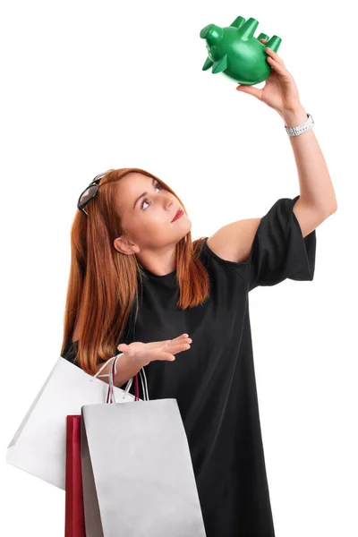 若い赤毛の女の子のショッピングバッグや空の貯金箱を保持し 彼女の顔に驚きの表現で 白い背景に孤立した 過剰支出の概念 金融債務の概念 ロイヤリティフリーのストック画像