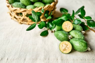 Keten masa örtüsü üzerinde taze yeşil feijoa meyveleri. Guava ailesinin Acca sellowiana meyveleri. C vitamini, sağlıklı beslenme. Seçici odak.