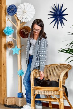 Kadınlar Noel hediyelerini geri dönüşümlü kağıda sarıp alternatif noel ağacı ve kağıt Noel süslemesiyle kara kedilerle oynuyorlar. Kış tatili.