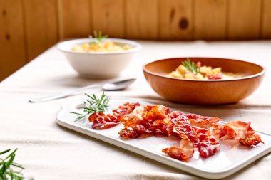 Balkabağı kremalı çorba için kızarmış domuz pastırması. Masada kil tabakta, keten masa örtüsüyle birlikte. Sonbahar sebze kremalı çorba püresi. Sağlıklı mevsimsel yemek.