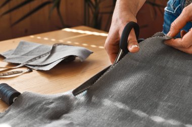 Kadın keten kumaş desenli bir kağıt kesiyor. Küçük stüdyodaki dikiş makinesinin terzisi. Moda atölyesi, terzilik, el yapımı kıyafet konsepti. Yavaş Moda Bilinci Tüketimi