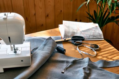 Kalıp kağıdı, keten kumaş, makas, dikiş makinesi ve diğerleri moda atölyesinde aksesuar dikiyorlar. Terzilik, el yapımı kıyafet konsepti. Yavaş Moda Bilinci Tüketimi