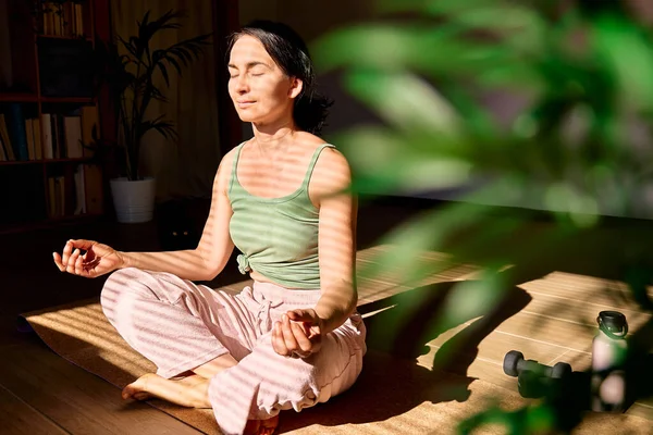 在家中练习瑜伽和冥想的女人坐在瑜伽垫上 闭着眼睛放松下来 记住冥想的概念 — 图库照片