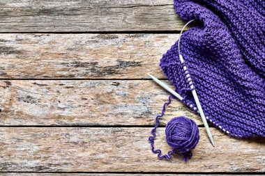 Menekşe yumağı yün yumağı, leyla eşarp ve yukarıdan masa görüşünde ahşap örgü iğneleri. Hobi olarak, metin için alanı olan bir hobi. Örgü örme, dikiş yapma kavramı. Çok neşeli bir renk..