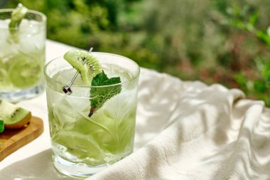 Soğuk yaz içecekleri ve içecekleri. Limonata, kivi, nane ve buzlu cam. Çeşnili alkolsüz kokteyl. Seçici odak.