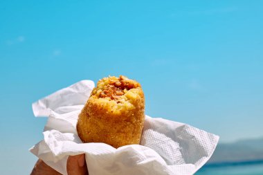 Typical Sicilian street food on seaside background. Hand of man 
