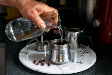 Adam mutfaktaki mocha 'da klasik İtalyan kahvesi hazırlıyor kahve makinesine su döküyor. Kahve freni. Sabah alışkanlığı.