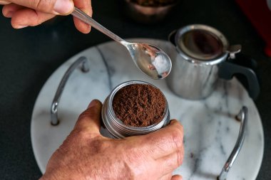Man preparing classic Italian coffee in the mocha in the kitchen, filling funnel of a moka pot with ground coffee. Coffee brake. Morning habit.