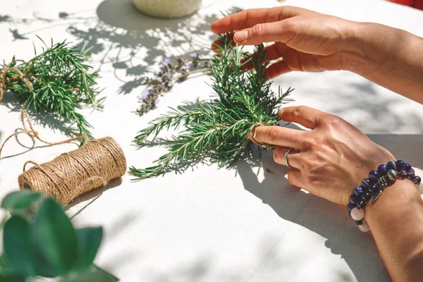 Alternative medicine. Collection and drying of herbs. Woman holding in her hands a bunch of rosemary. Herbalist woman preparing fresh scented organic herbs for natural herbal methods of treatment.