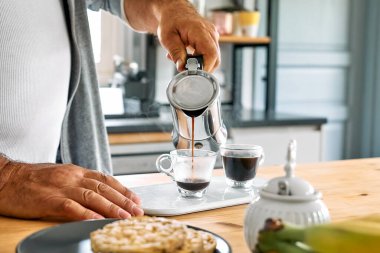 Adam mutfaktaki mocha 'da klasik İtalyan kahvesi hazırlıyor. Moka pot 'tan küçük cam kahve fincanına kahve dolduruyorum. Kahve freni. Sabah alışkanlığı.