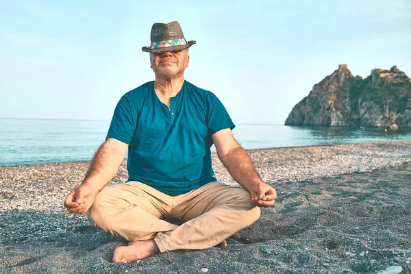 中年男人头戴草帽 荷花坐姿 背景在海滨静坐的画像 休闲活动 生活方式及自然概念 — 图库照片