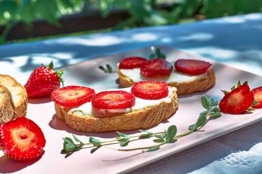 Yazın çilekli sandviç yapan bir kadın. Tost ekmeği kesen kadın eller. Sağlıklı beslenme, meyve diyeti kahvaltısı..
