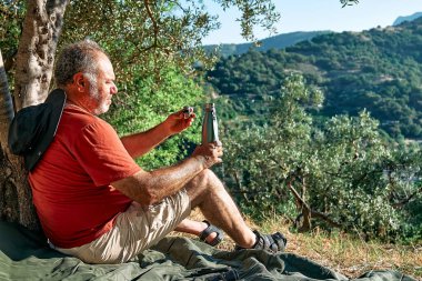 Turist zeytinlikte dinleniyor, termal çelik şişeden su içiyor, seyahat ediyor ya da dışarıda egzersiz yapıyor. Aktif insanlar, yürüyüş, sağlıklı yaşam tarzı ve uyum kavramı. Doğayla birlik.