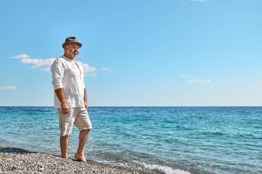 Kumsalda yürüyen mutlu orta yaşlı sakallı adam. Boş zaman aktiviteleri, refah, özgürlük, turizm, yaşam tarzı ve doğa kavramı. Yaz aylarında turizm.