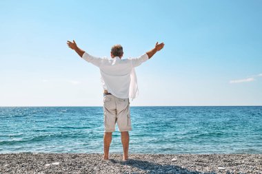 Mutlu orta yaşlı turist denizde özgürlüğün tadını çıkarıyor. Sağlık, başarı, özgürlük ve seyahat kavramı. Yaz tatilinde.