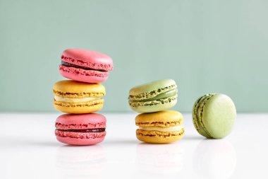 Colorful french macarons on pastel background. Tasty cakes macaroon of different colors. Strawberry, lime and lemon almond cookies, pastel colors.