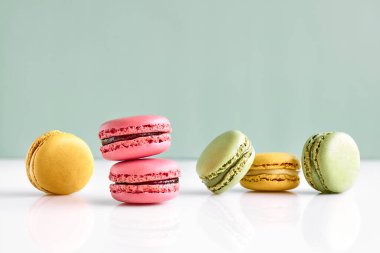 Colorful french macarons on pastel background. Tasty cakes macaroon of different colors. Strawberry, lime and lemon almond cookies, pastel colors.