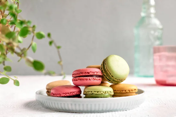 Colorful french macarons on pastel background. Tasty cake macaroon of different colors in the plate. Almond cookies, pastel colors.