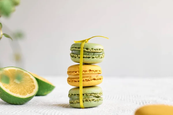 Colorful french macarons on pastel background. Tasty cake macaroon of different colors. Lemon and lime almond cookies, pastel colors.