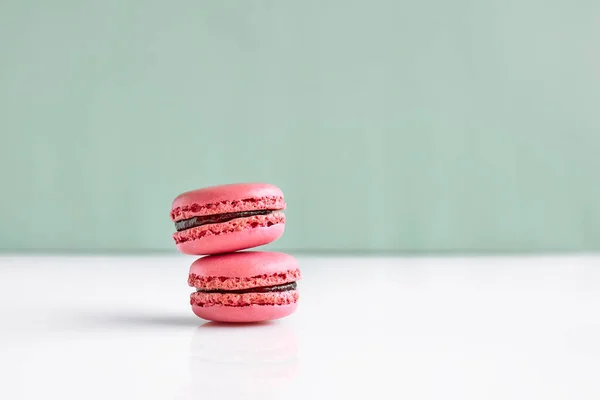 Pink french macarons on pastel background. Tasty cake macaroon of different colors. Strawberry almond cookies, pastel colors.