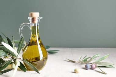 Extra virgin olive oil and olive branch in the bottle on the table with linen tablecloth. Healthy mediterranean food.