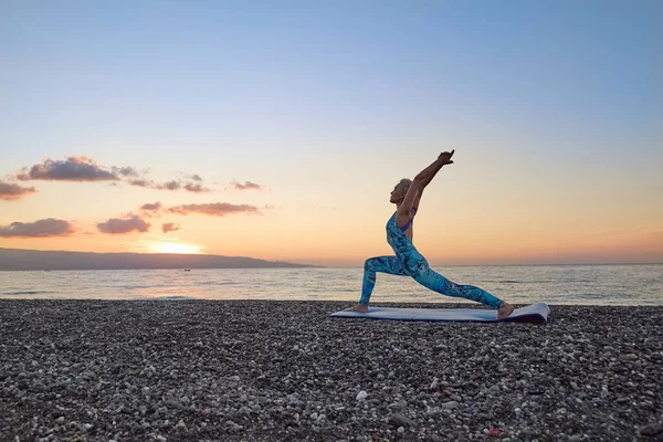 Młoda Kobieta Ćwiczy Jogę Plaży Wschodzie Słońca Robi Virabhadrasana Lub — Zdjęcie stockowe