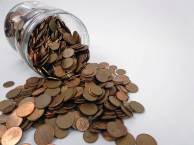Overturned glass jar with coins coming out of it, isolated on white background