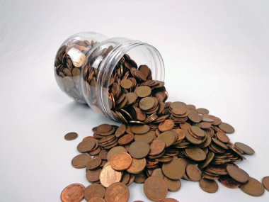 Overturned glass jar with coins coming out of it, isolated on white background