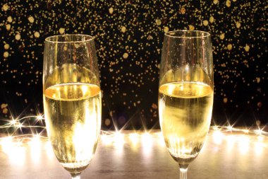 Şampanya fincanlarının yakın planında parıltılardan oluşan ışıklarla çevrili.